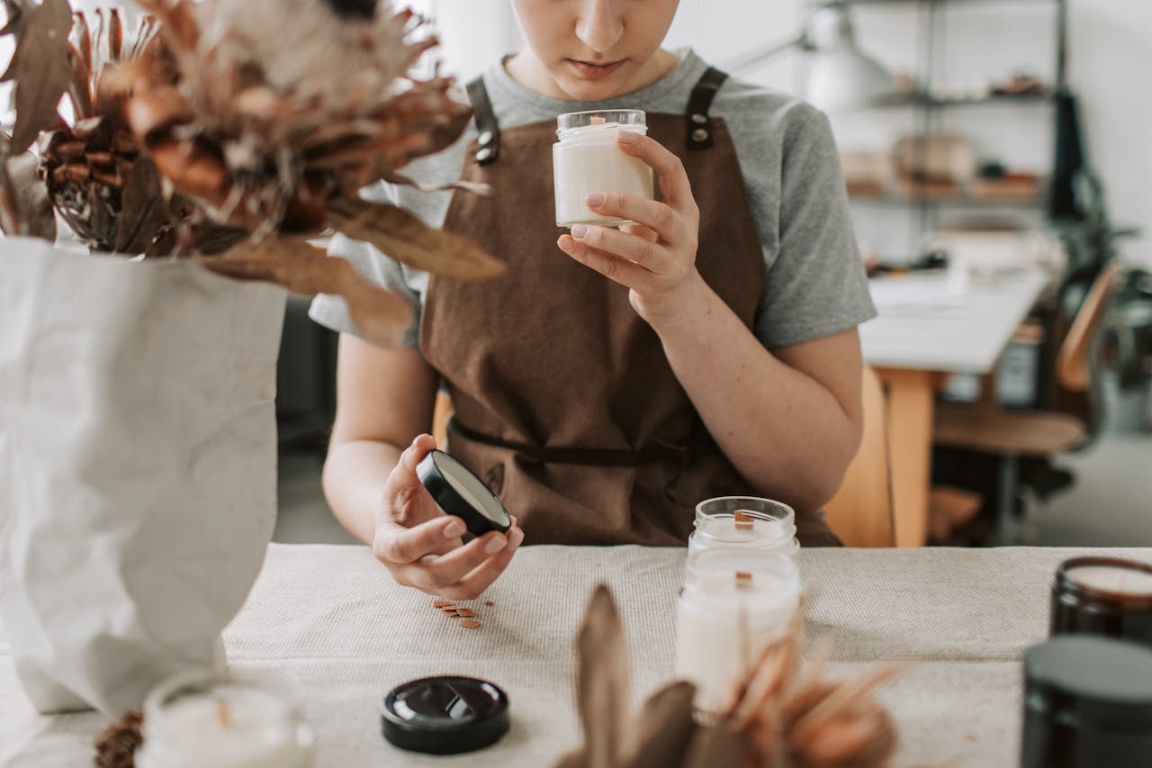 about-us-01 A woman crafting candles in a rustic workshop, focusing on scents and quality.