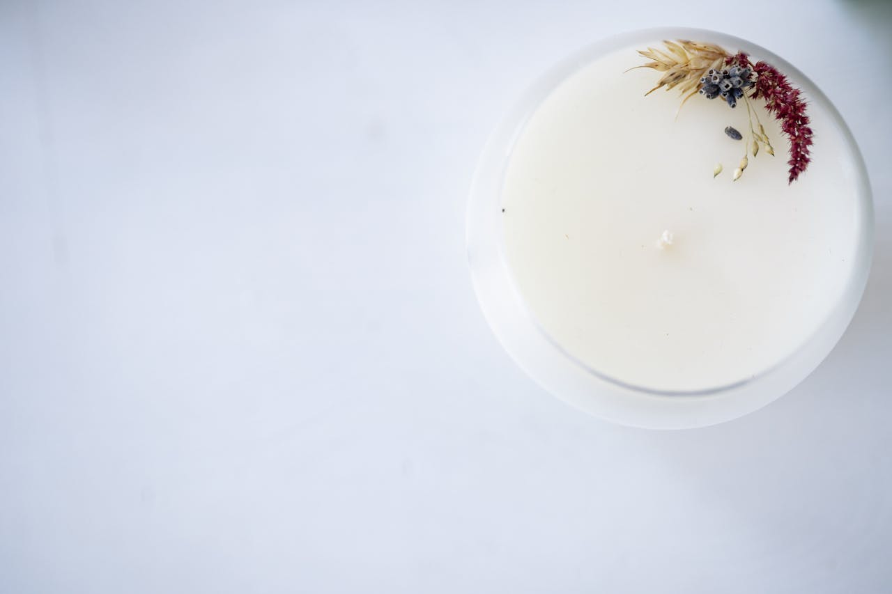 services-04 Overhead shot of a soy candle with decorative dried flowers and ample copy space.